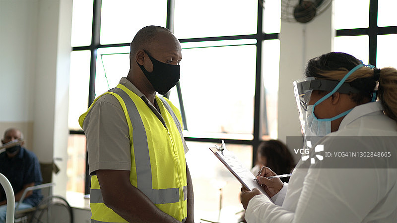 医生询问工人病人并填写表格（戴口罩）图片素材