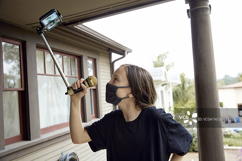 小女孩戴着口罩在家录制视频图片素材