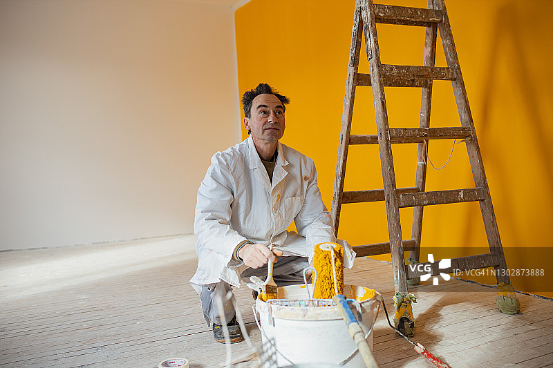 油漆工人在桶里混合黄色油漆图片素材