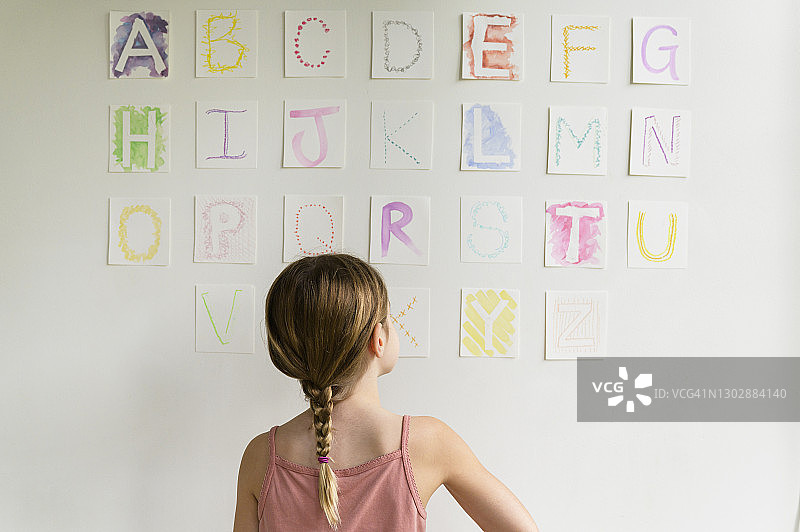 看着墙上字母的女孩（8-9岁）的背影图片素材