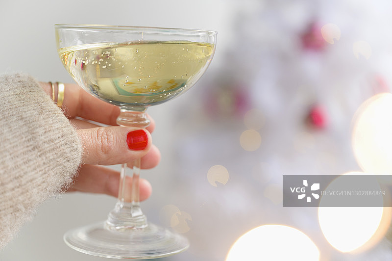 圣诞树旁手持香槟酒杯图片素材