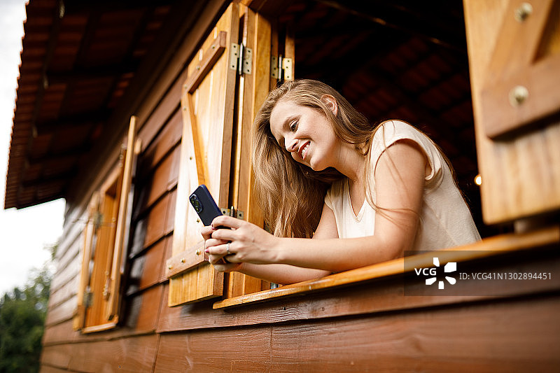 年轻女子在小屋里用手机看视频图片素材