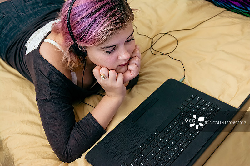 少女手捧着头，看着笔记本电脑图片素材
