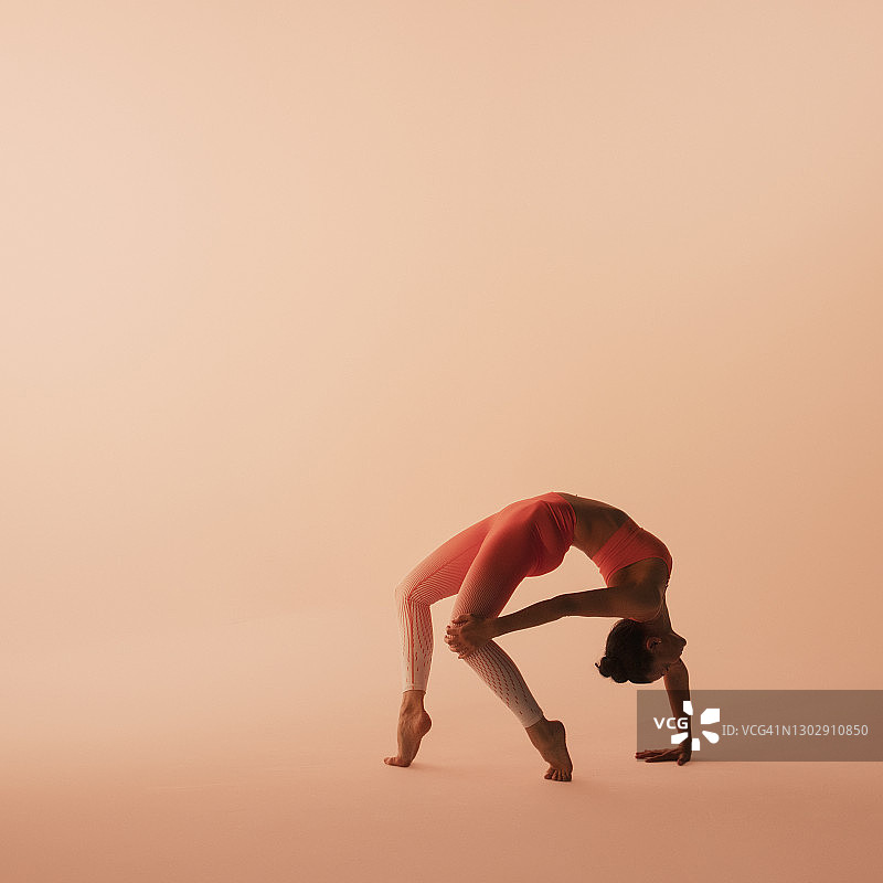 年长的运动型女人穿着运动服、裤子和上衣，练习瑜伽，工作室拍摄图片素材