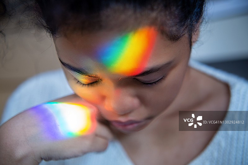 女孩的脸映出彩虹光图片素材