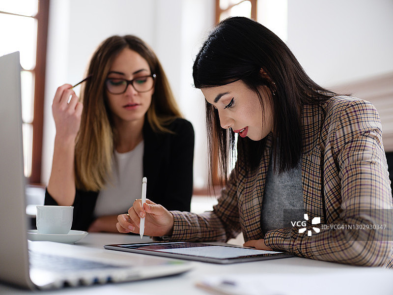 女商人们在办公室使用笔记本电脑和数位板讨论新项目图片素材