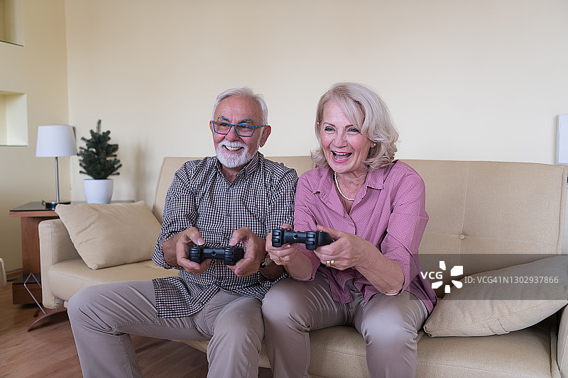 帅气的老年男人和他的老伴在家一起玩游戏机图片素材