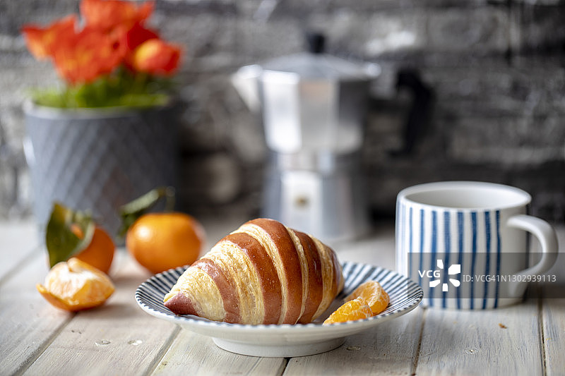 舒适的咖啡休息：甜羊角面包、新鲜橙子和咖啡图片素材