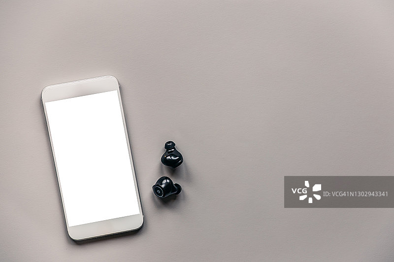 灰色背景上的带无线耳机的智能手机模型图片素材