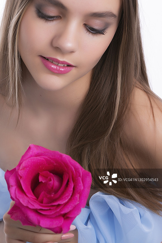 手持粉色玫瑰的美丽年轻女人图片素材