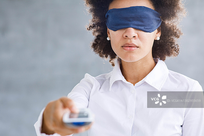 蒙眼女子在无法看到电视真实内容的情况下换频道图片素材