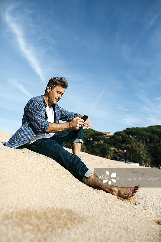 男人在海滩边使用手机图片素材