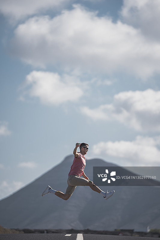 在西班牙兰萨罗特岛高速公路上跳跃的快乐男游客图片素材