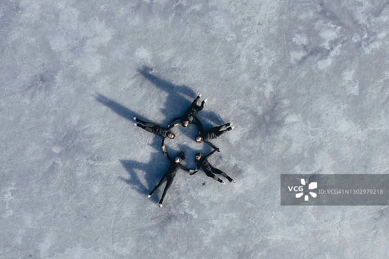 冰冻湖面上，一群女子花样滑冰运动员躺在一起的航拍图片素材