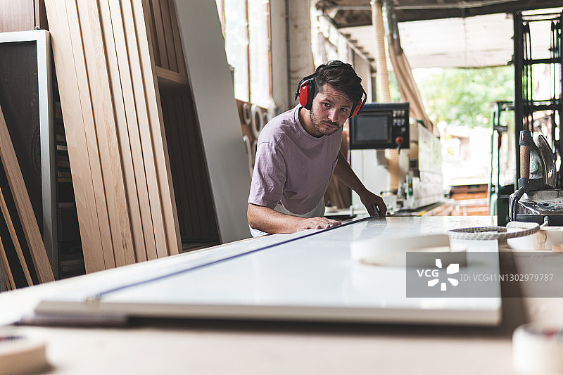木匠在工作台上用卷尺测量木板图片素材