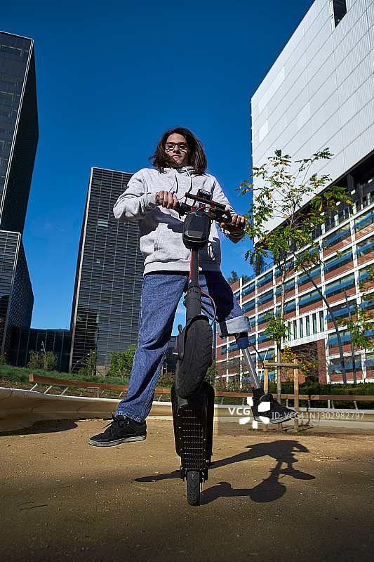 在城市游乐场，年轻残疾男子在电动滑板车上练习特技图片素材