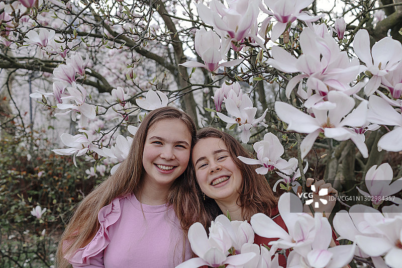 在公园里玉兰树旁的快乐女性朋友图片素材