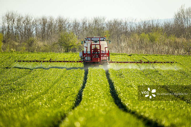 拖拉机在绿色农场喷洒农作物图片素材