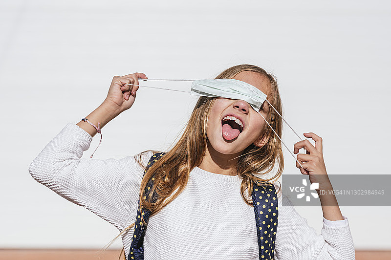 疫情期间，戴防护口罩、吐舌头的顽皮女孩图片素材