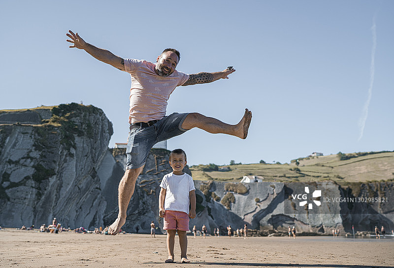 快乐的父亲在海滩上跳过儿子图片素材