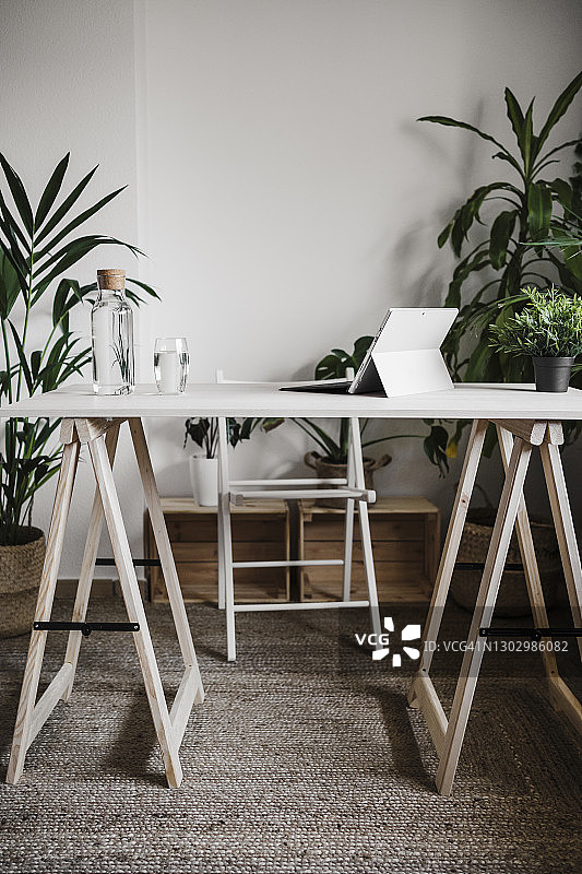 办公室折叠桌椅上的数码平板电脑和水瓶图片素材