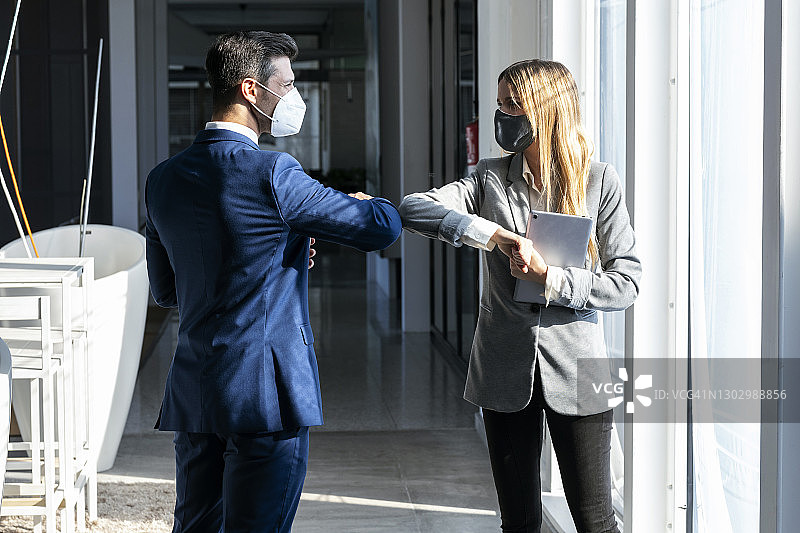 疫情期间，办公室里商人与同事互相碰肘图片素材