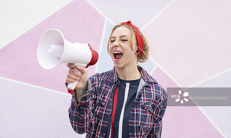 女人靠墙用扩音器尖叫图片素材