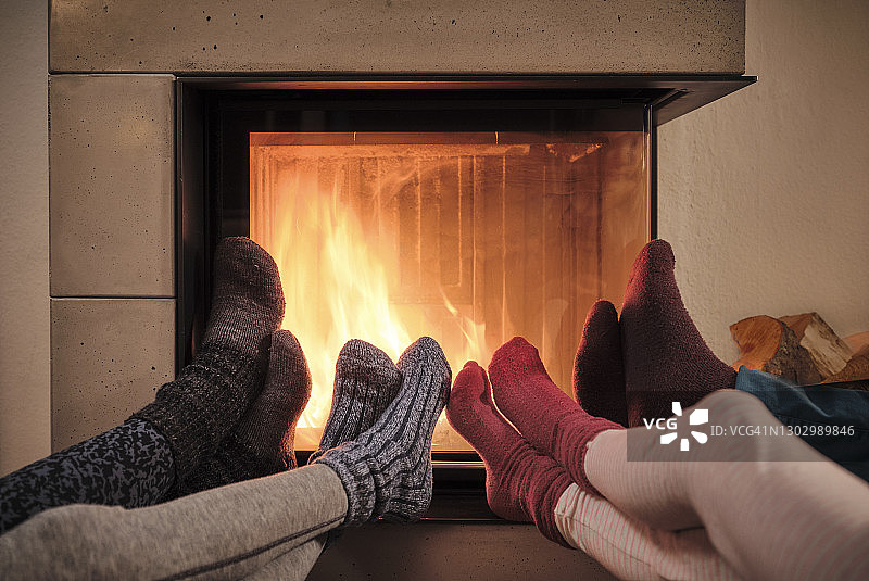 一家人在客厅壁炉旁穿着羊毛袜暖脚图片素材