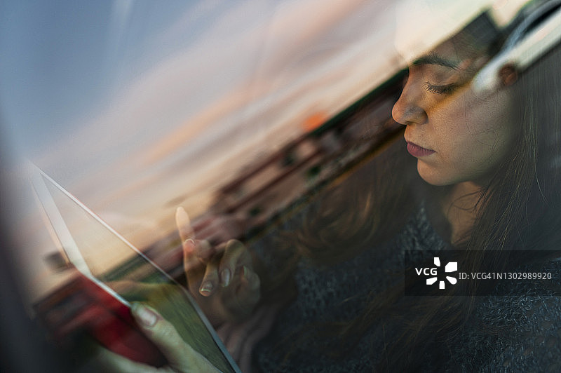 年轻女子在车内使用平板电脑（玻璃窗视角）图片素材