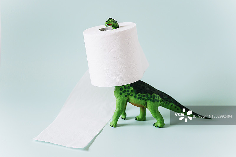 薄荷绿背景下脖子上缠着一卷卫生纸的梁龙恐龙玩具图片素材