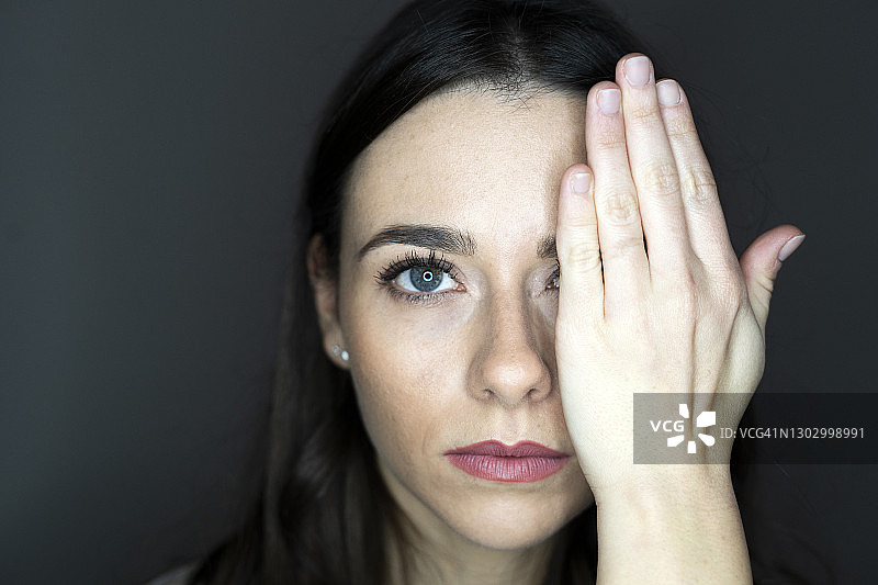 在工作室用手遮住一只眼睛的女人图片素材