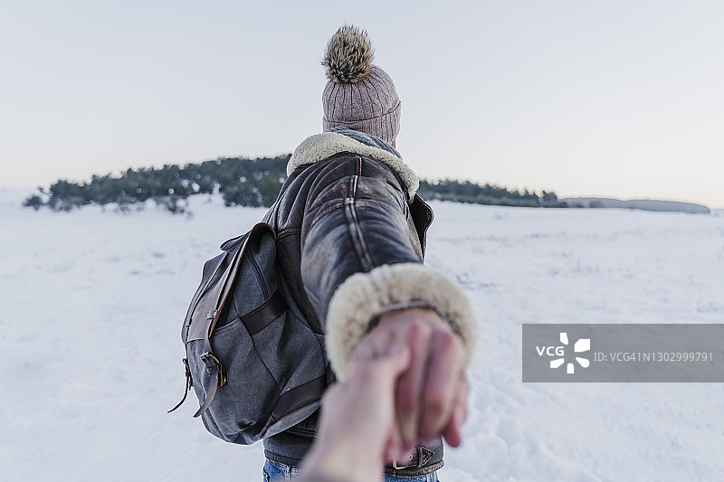 男人在日落时牵着女人的手在雪地上行走图片素材