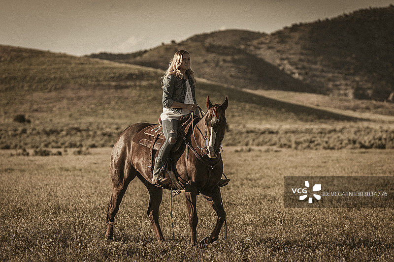 犹他州瓦萨奇山脉下的赛马场景，年轻女牛仔准备就绪图片素材