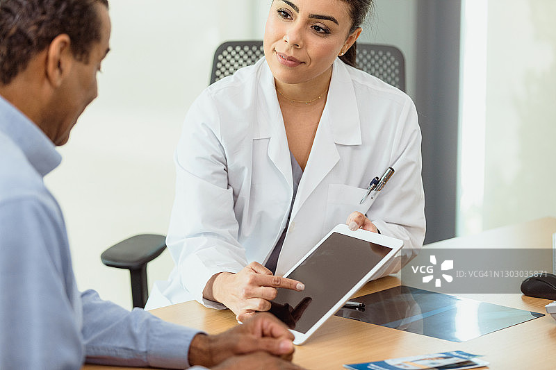 女医生用平板电脑向病人讲解手机应用图片素材