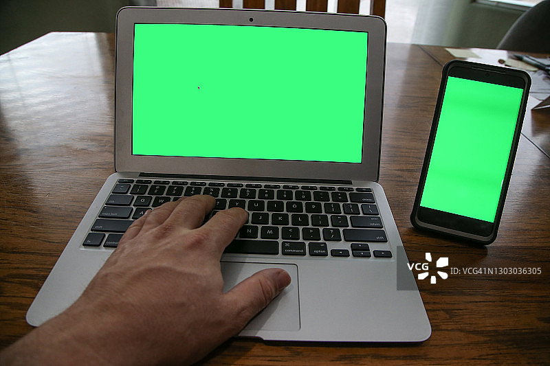 使用带绿屏的笔记本电脑和手机的视角图片素材