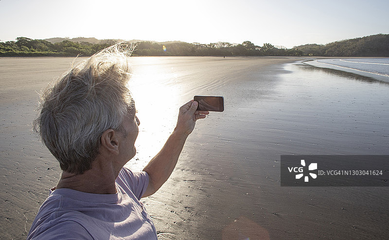 男人拍摄空旷的海滩日出图片素材