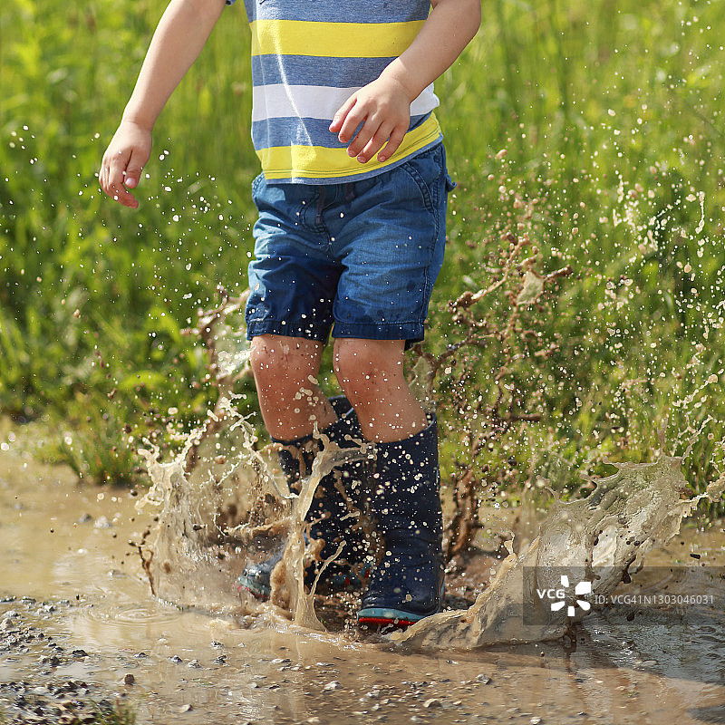 男孩在水坑中跳跃图片素材