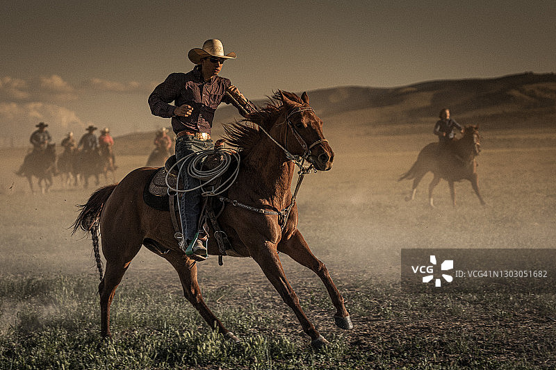 前景年轻牛仔与马背景牛仔监督马群图片素材