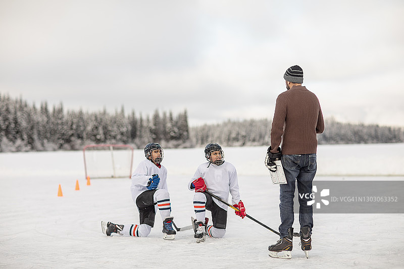 户外溜冰场上，曲棍球运动员跪地听教练讲解图片素材