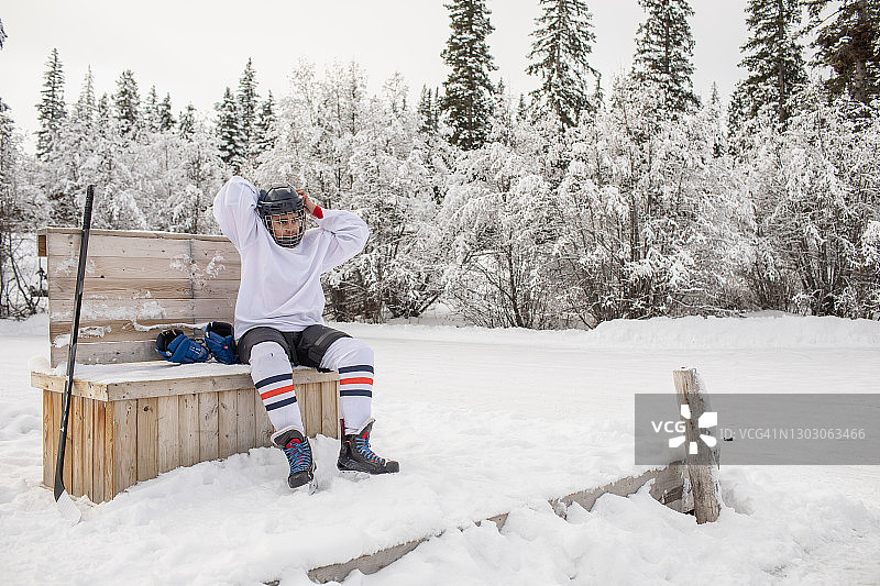 在户外溜冰场上系紧头盔的冰球少年图片素材