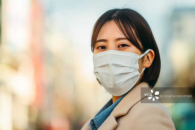 在城市街道戴防护口罩认真注视镜头的女人图片素材