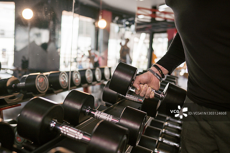 在健身房举哑铃的健壮男人图片素材