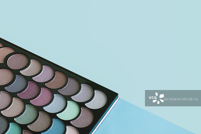 蓝色背景上彩色化妆盘的特写。 美容概念图片素材