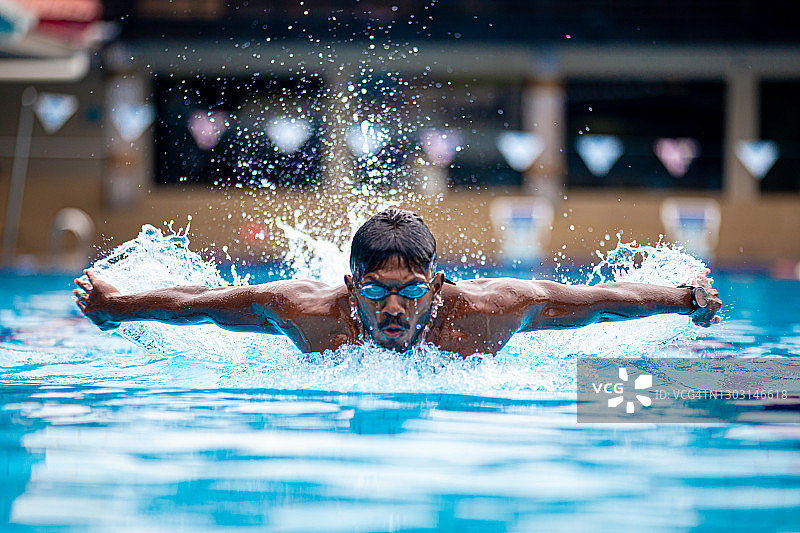 亚裔印度游泳运动员在游泳池进行蝶泳训练图片素材