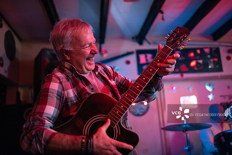 年长的男人和他的乐队在舞台上弹吉他图片素材