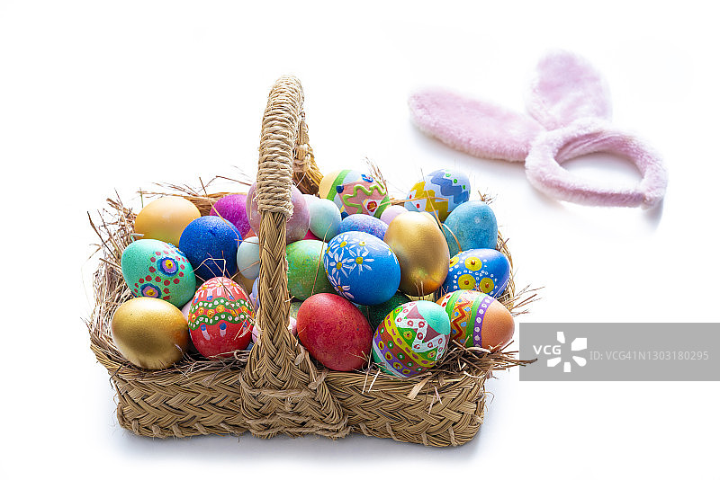 手绘复活节彩蛋与草编篮子，白色背景和春季树叶图片素材