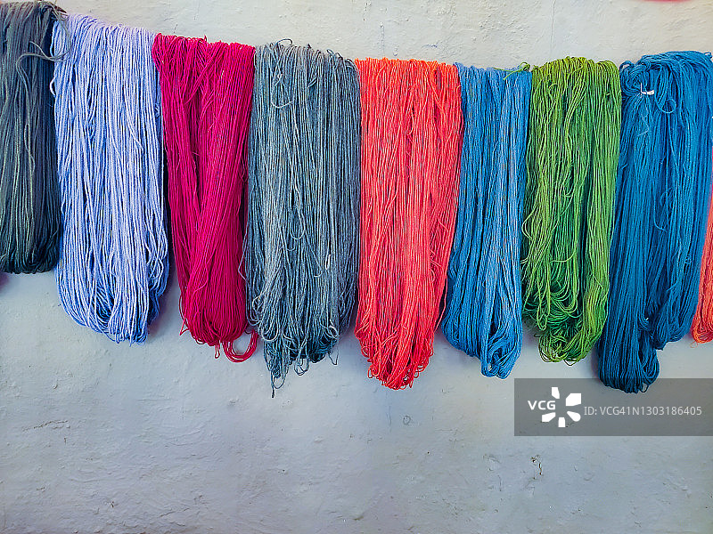 白墙上悬挂的彩色纱线图片素材