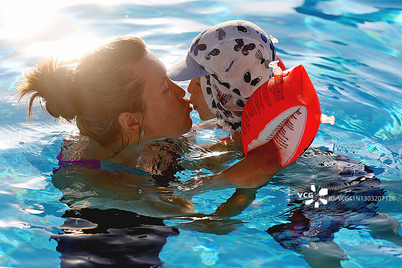 可爱男孩和妈妈夏日泳池玩耍图片素材