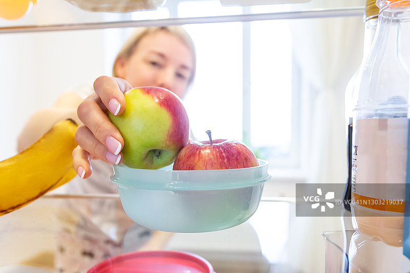 健康素食，女性的苹果减肥餐。用塑料容器在冰箱中储存食物图片素材