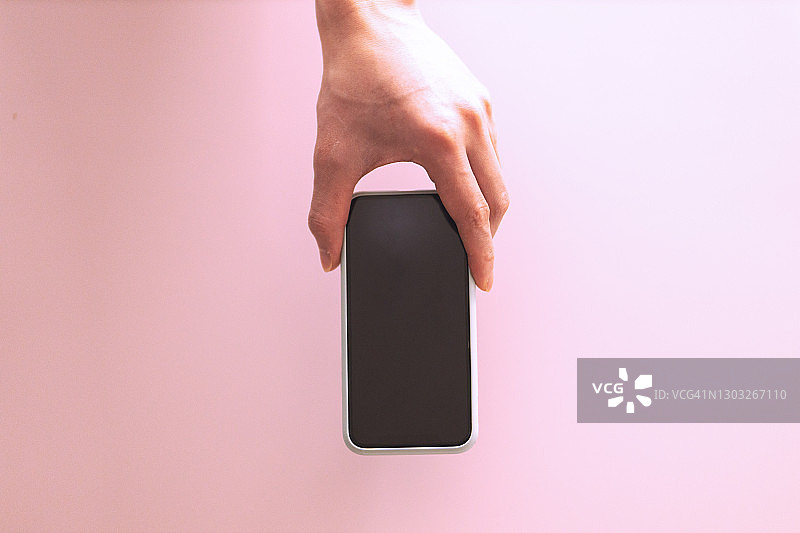 在粉色背景上拿着智能手机的男人图片素材